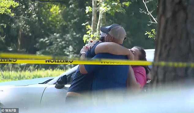 Family hugs at the crime scene Monday after the discovery of the bodies