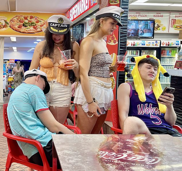 Pictured: Partygoers wearing fancy dress hats were seen gathering outside a food court early in the morning with drinks in hand