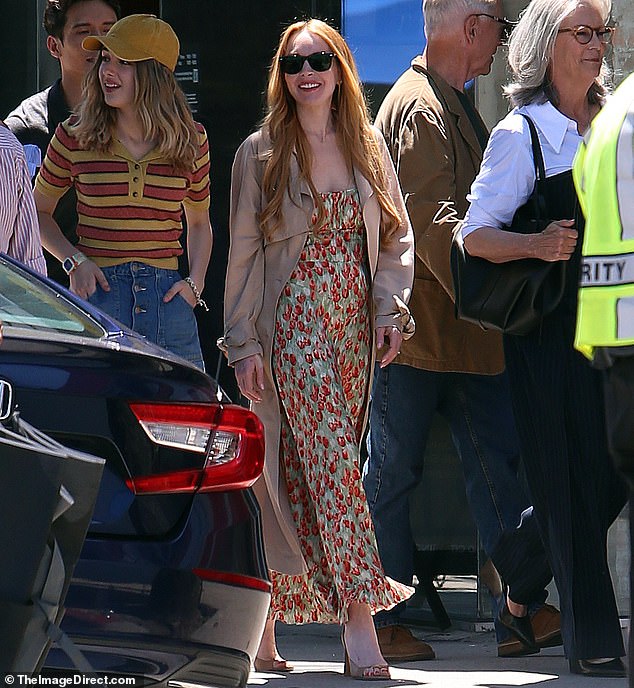 Lohan looked effortlessly chic in a green and red floral maxi dress, which she paired with a brown trench coat