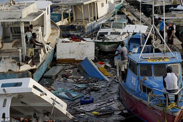 A fisherman throws a rope over boats damaged by Hurricane Beryl at Bridgetown Fisheries in Barbados