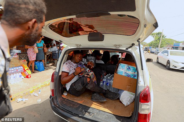 A local Jamaican man steps into the back of a taxi filled with supplies such as water and perishables as people prepare for Hurricane Beryl in Kingston