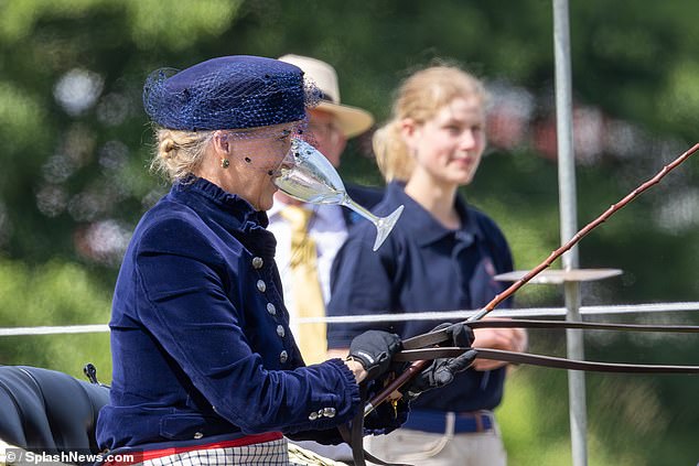 The Duchess of Edinburgh is pictured with a wine glass between her teeth as she drives a carriage