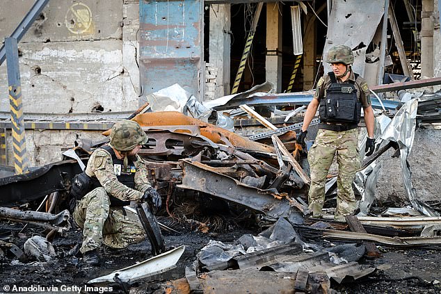 Soldiers work in the area as the building and surrounding vehicles lie in ruins after a Russian airstrike on a post office in Ukraine's Kharkiv region