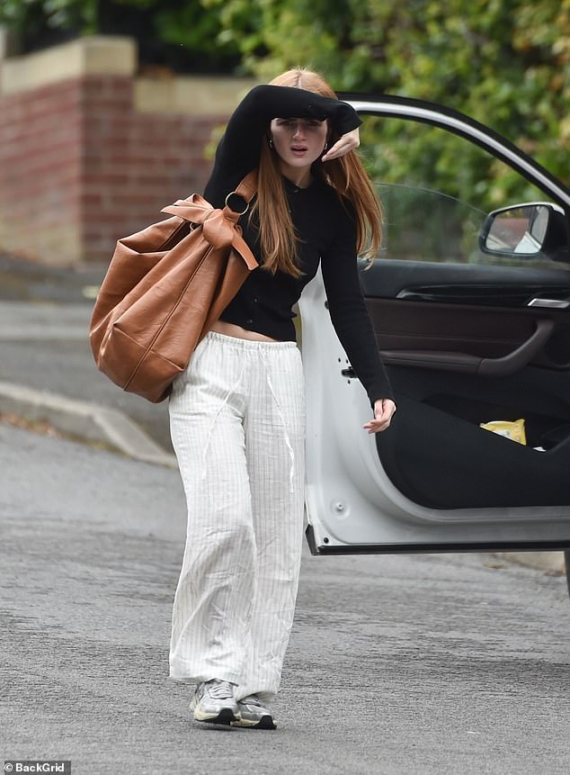 Maisie completed her look with a pair of striped, loose-fitting trousers in off-white, a large brown handbag and grey sneakers