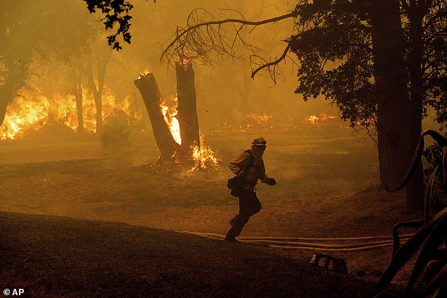 A firefighter runs as he battles the Thompson Fire raging Tuesday in Oroville, California