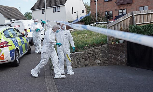 A forensic team steps under the police tape that cordoned off the scene of the double murder