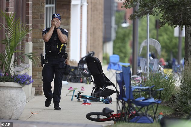 A police officer bows his head in grief next to abandoned strollers and chairs after a shooting that left six people dead in Highland Park, Illinois, in 2022
