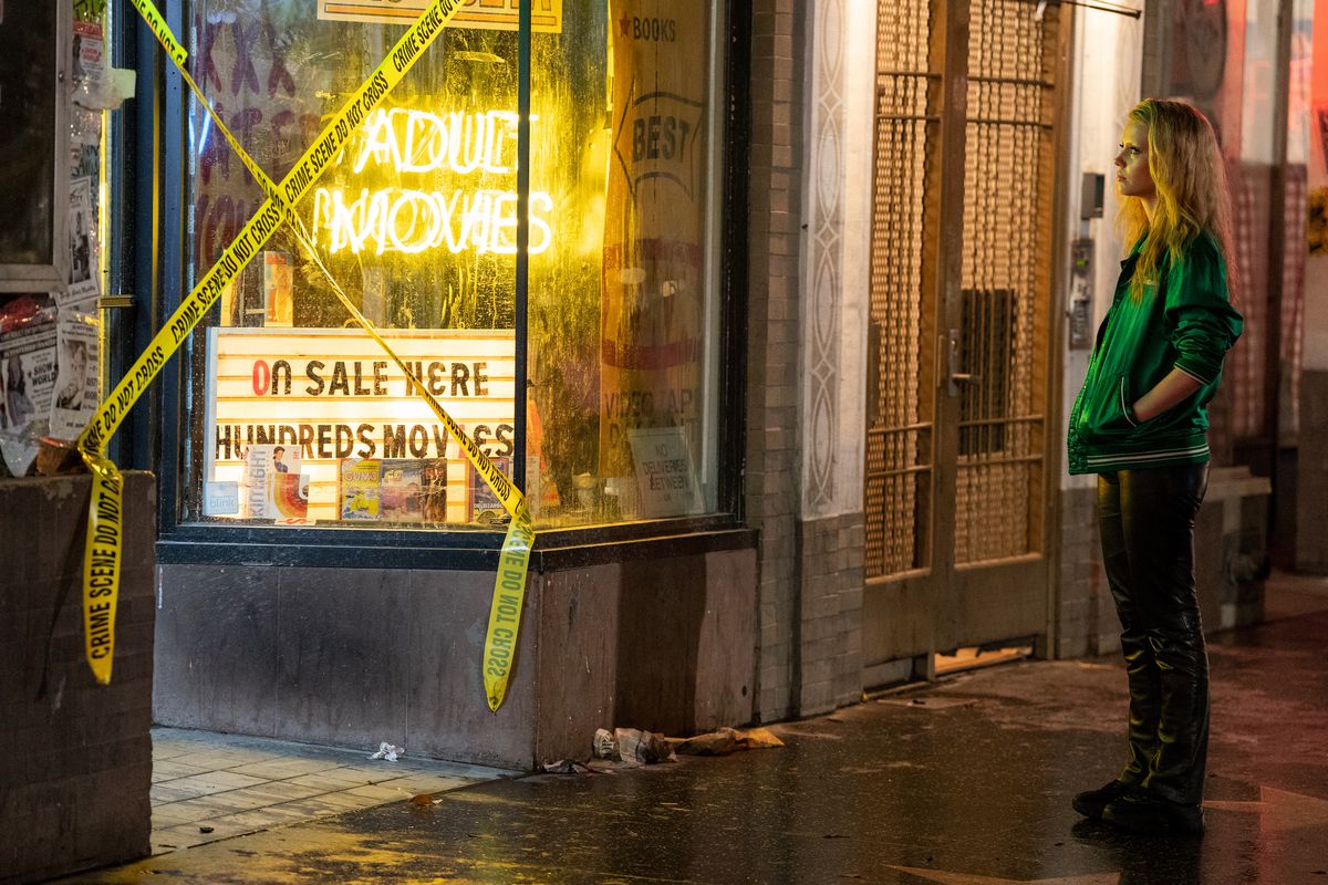 Maxine (Mia Goth) stands outside a store with a bright neon yellow sign that reads 