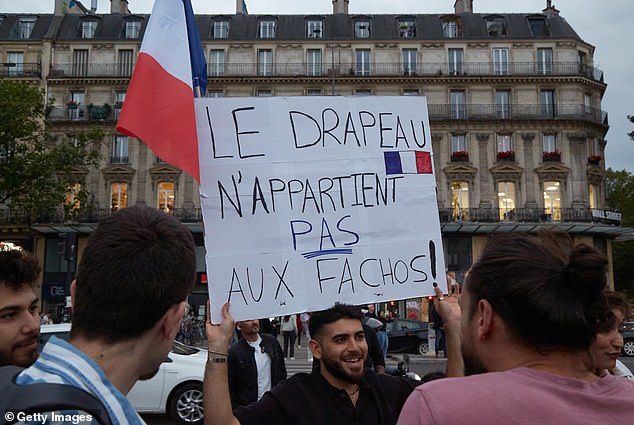 A man holds a sign saying the French flag is not for fascists as tens of thousands of people gather in Paris to protest against the far-right
