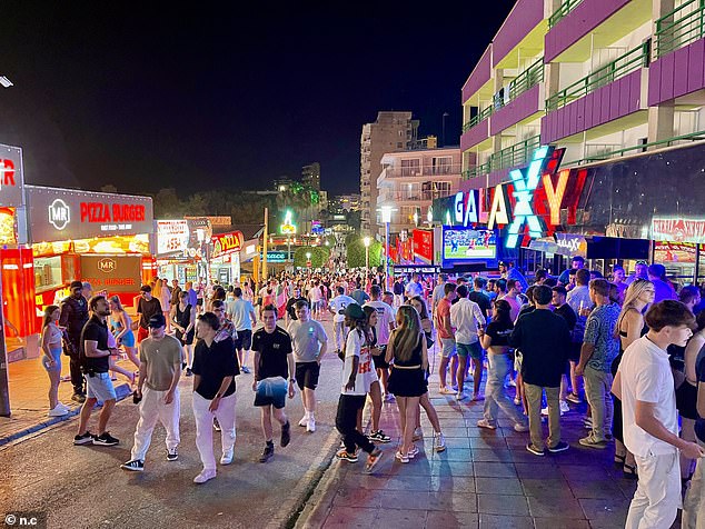 The 45-year-old was found unconscious on the resort's Martin Ros Street, near the bustling Punta Ballena strip, after the alarm was raised at around 4.30am on Monday morning. Pictured: Tourists are seen in Magaluf on Sunday evening