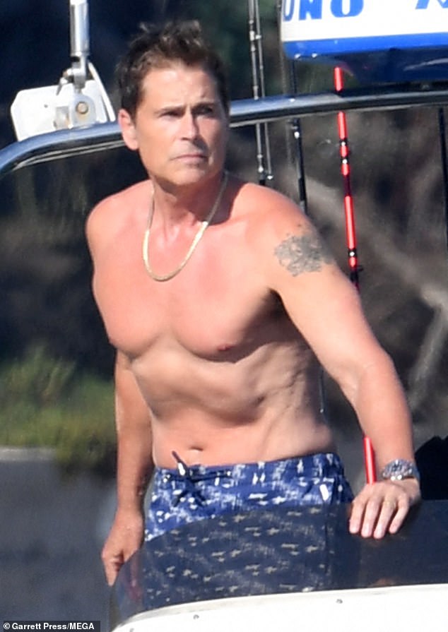 The West Wing star opted for a blue and white patterned swim trunks and wore a silver chain around his neck