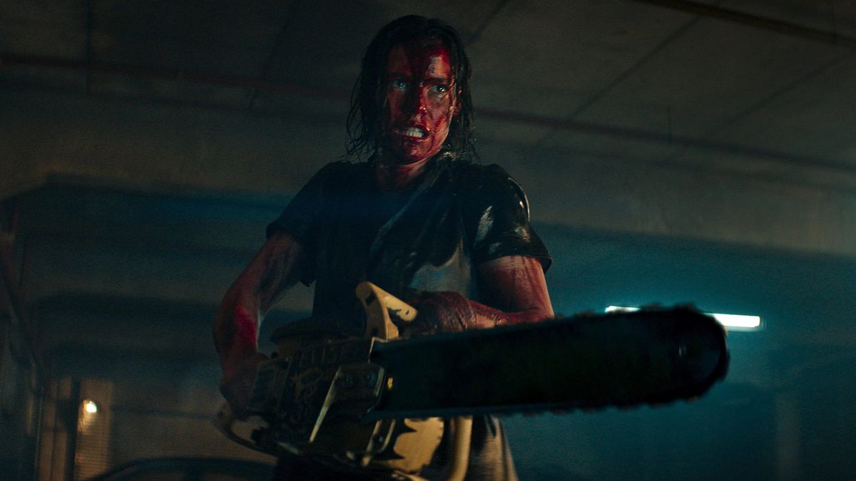 Lily Sullivan as Bethany “Beth” Bixler covered in blood and brandishing a chainsaw in Evil Dead Rise.