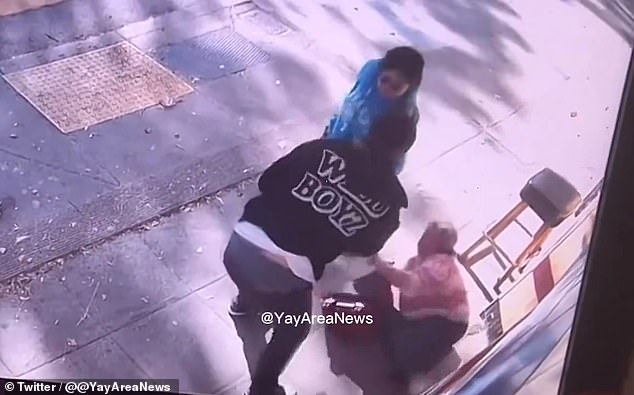 In the video circulating on social media, the woman follows another bystander with a bag and a piece of luggage at her side. The woman looks up at the man, who is wearing a black zip-up hoodie, a white shirt and black pants, before she is then struck on the head and falls to the ground