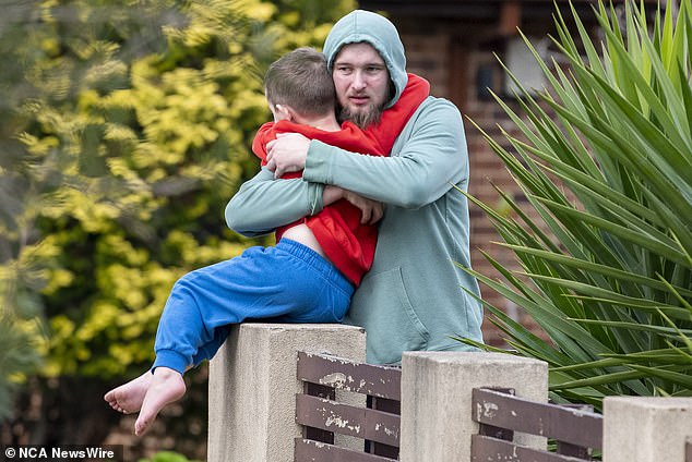 Neighbour Jarrod Hawkins (pictured hugging his son) was praised for rushing into the burning home. Police said Mr Hawkins' actions 'saved more lives from loss'