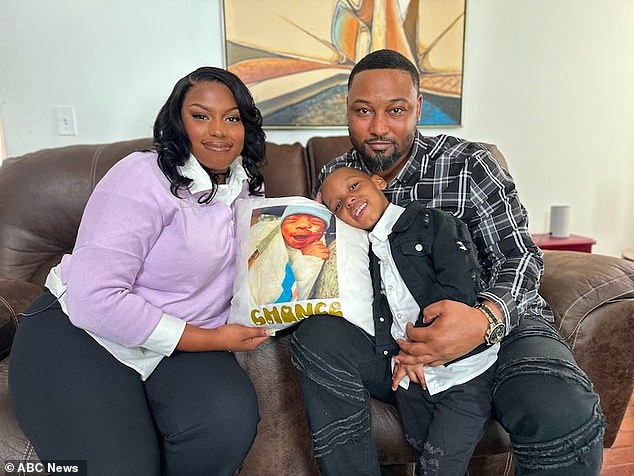 Jasmine Watson sits with her partner, Cedric Dean, and their son Chase, 4. The pillow features Chance Dean, who died of NEC in March 2020.