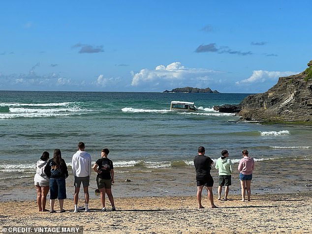 The crowd watches as the ice cream truck is battered by the waves