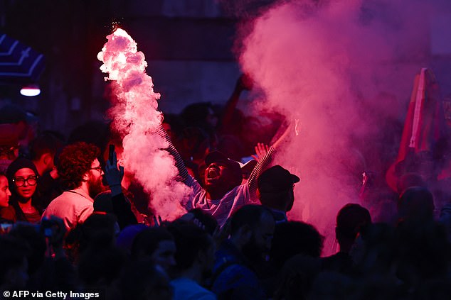 Supporters light red flares during the election night of the left-wing party La France Insoumise (LFI) after the first results of the second round of the French parliamentary elections at La Rotonde Stalingrad in Paris on July 7, 2024.