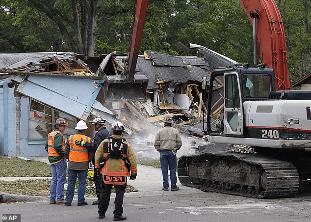 Demolition experts watch as the home is destroyed after a sinkhole opened late that evening, swallowing Bush, 37, in Seffner on March 3, 2013.