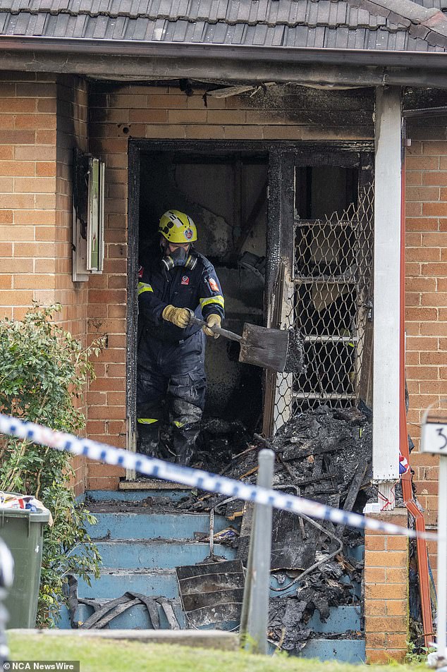 Pictured: A firefighter and rescue worker clearing soot and debris from the site on Sunday