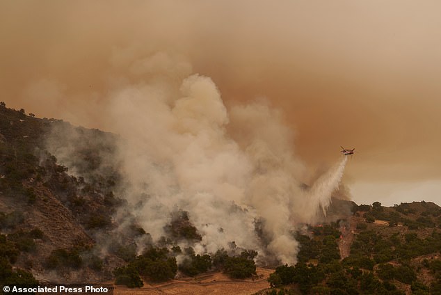 A helicopter dropping water drops flames on the advancing Lake Fire in Los Olivos, Calif., Saturday, July 6, 2024. (AP Photo/Eric Thayer)