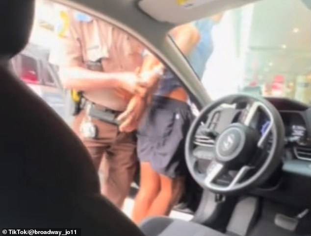 Here, the passenger leans over to film the officer handcuffing his Uber driver