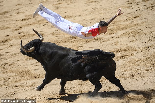 a "recording device" (bull groomer) jumps over a bull in the Plaza de Toros bullring during a show after the first day of the San Fermin festival in Pamplona, ​​​​northern Spain, on July 7, 2024