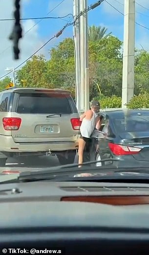 She chases the car and tries to get in through the front door, but the front door closes and her leg gets caught between the door and a parked SUV.