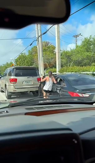 She chases the car and tries to get in through the front door, but the front door closes and her leg gets caught between the door and a parked SUV.