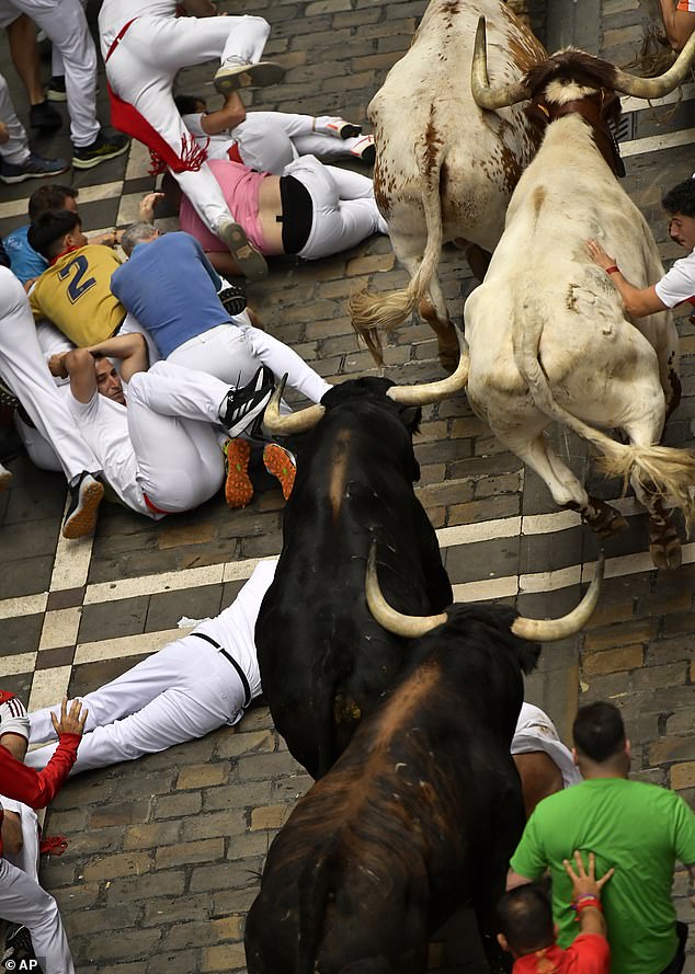 Revellers fall over during the third day of the Running of the Bulls in Pamplona on Tuesday