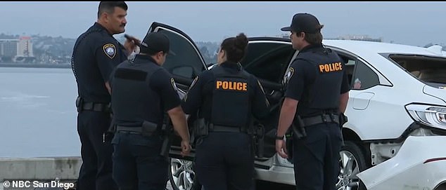 San Diego police stand around Tran's waterlogged and badly damaged car after divers pulled Tran's body from the car