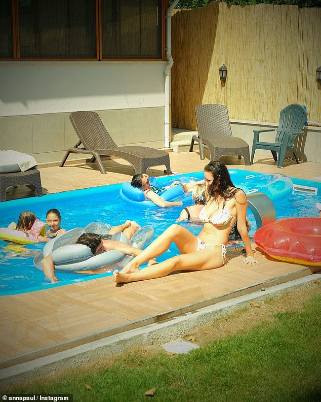 In a photo, Anna stretches her body by a pool, while the dark-haired hunk smiles at her as she sits on an inflatable