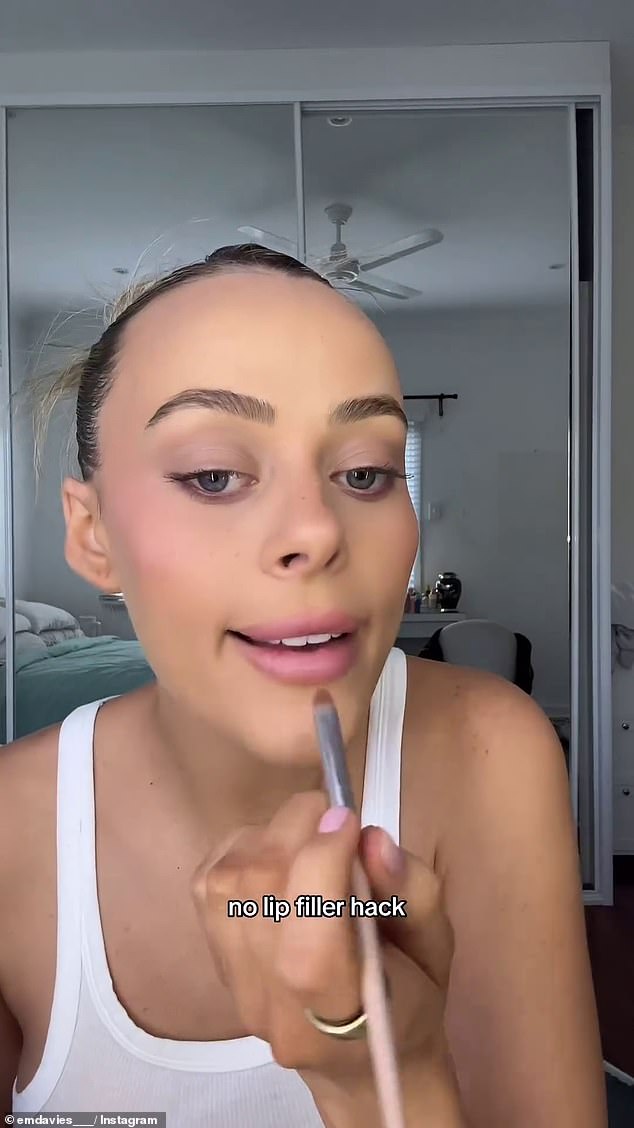 Em showed her followers that she takes a small amount of bronzer on the end of a brush and draws it partially along the edges of her lips