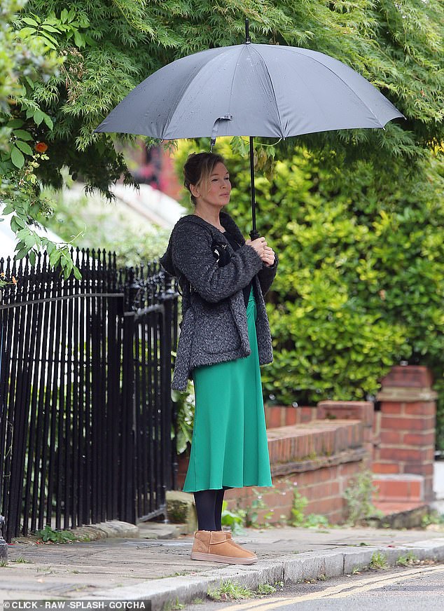 At one point she wore a flashy green skirt and a fluffy gray jacket while trying to stay dry with a large umbrella