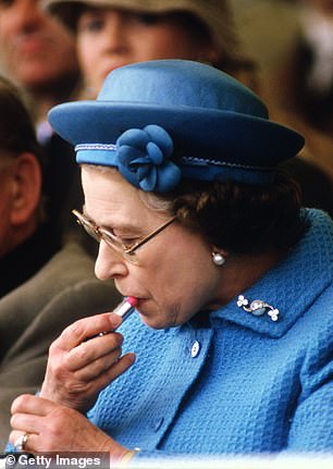 Queen Elizabeth II applies lipstick in the Royal Box at the Windsor Horse Show on May 11, 1985