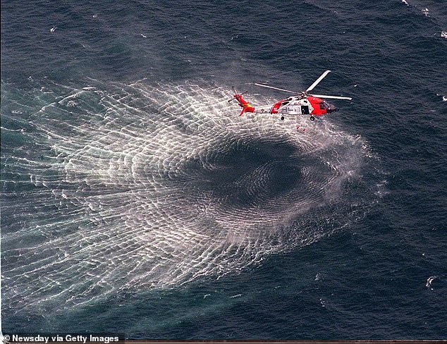 July 17, 1999: A Coast Guard helicopter lifts a rescue swimmer from the water during the search for wreckage from JFK Jr.'s plane.