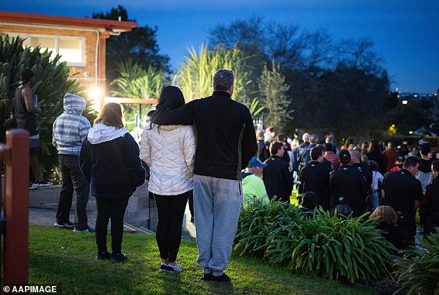 A couple support each other during Thursday night's vigil at Chifley Park in Lalor Park in memory of three young children believed to have been killed in a house fire