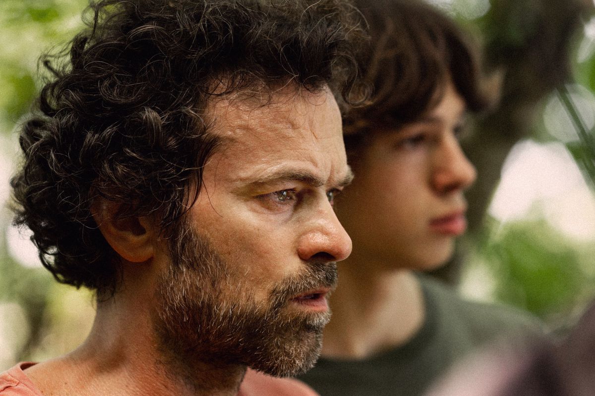 Romain Duris and Paul Kircher, standing in a forest, look in surprise at something off-screen in The Animal Kingdom