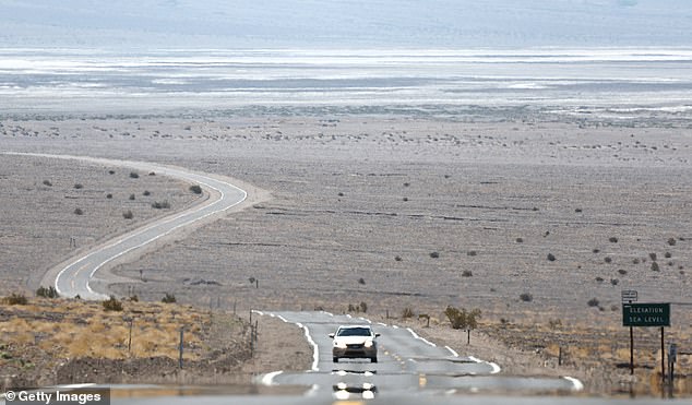 A vehicle drives as heat waves sparkle on the asphalt. Death Valley is the hottest and driest place in the United States