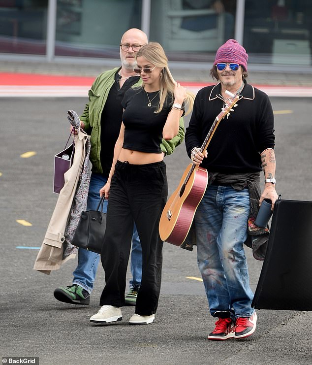 Looking cool and grungy in a red beanie, baggy jeans, sneakers and sunglasses, he held his guitar, perhaps serenading his potential new love.