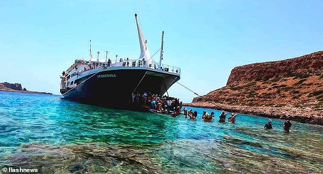 Passengers can be seen exiting the ferry hatch and walking through the water