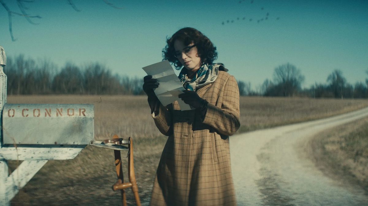 Maya Hawke as Flannery O'Connor reads a letter while standing next to her open mailbox in Wildcat.