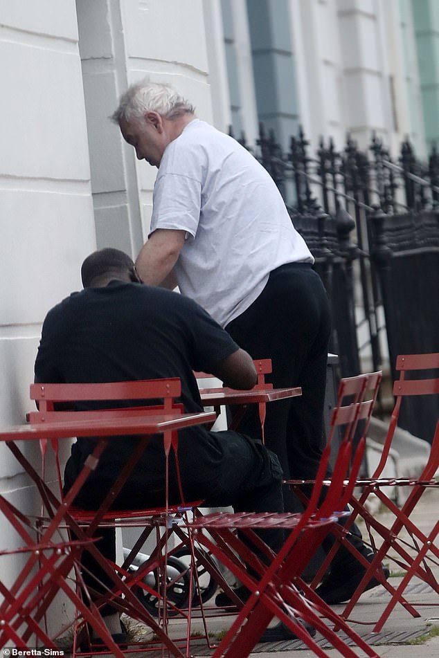 Eamonn looked casual in a grey T-shirt and black trousers as he struggled to get into a London cafe on Friday