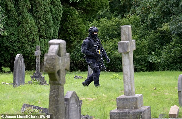 Police have launched a major manhunt for Clifford, who was found with serious injuries at Lavender Hill Cemetery in Enfield, North London. Pictured is an armed police officer on patrol at the cemetery