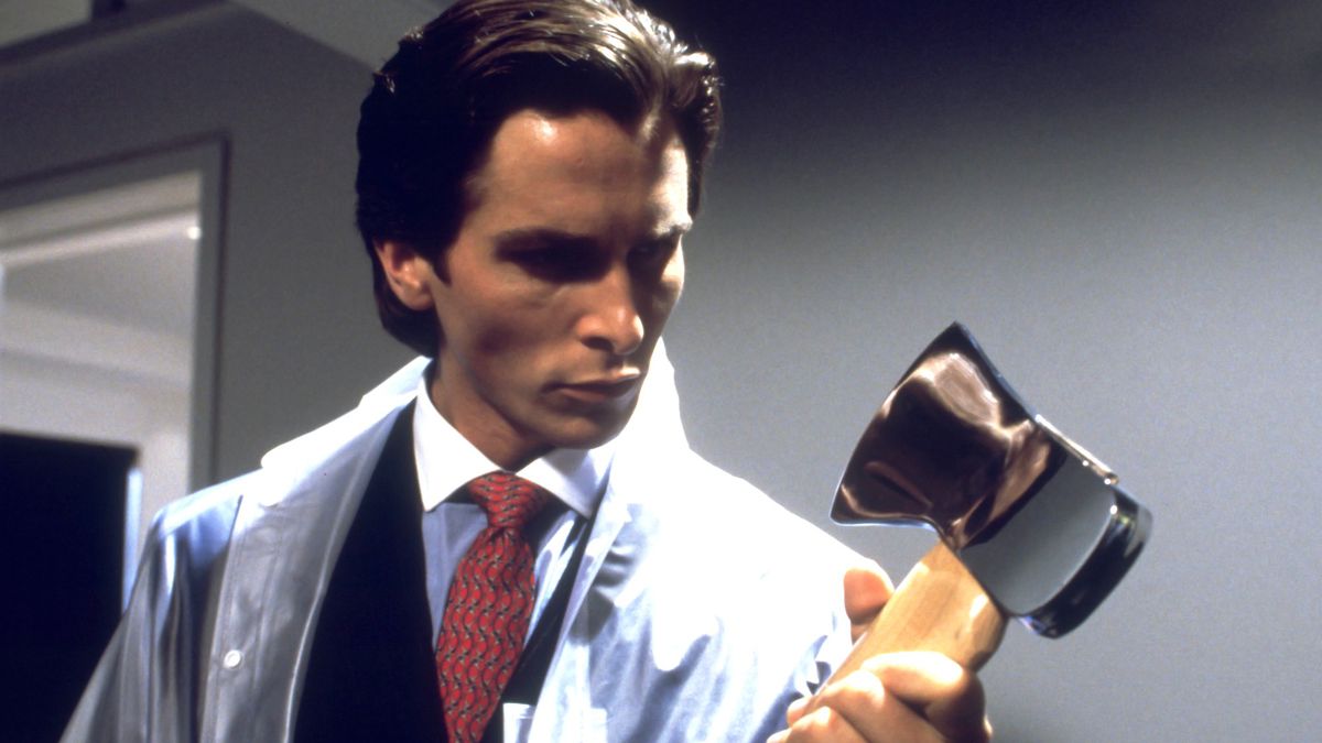 Patrick Bateman (Christian Bale) holds an axe while wearing a suit under a plastic poncho in American Psycho