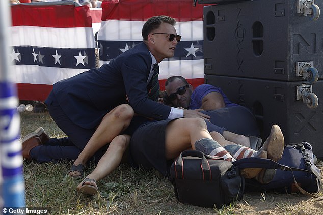 A Secret Service agent and members of the crowd take cover as gunshots are heard