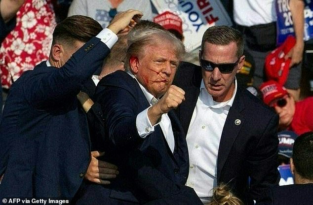 Donald Trump is seen with blood on his face, surrounded by Secret Service agents