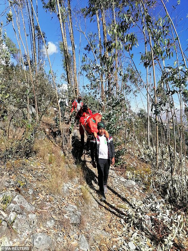 Peruvian mountain police and mountain rescue workers transport the remains of American climber Bill down the mountain