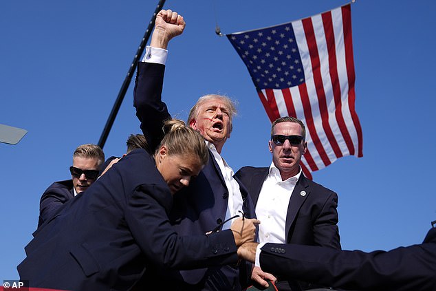 Former President Donald Trump is surrounded by U.S. Secret Service agents after he was shot during a campaign rally in Butler, Pennsylvania, on Saturday, July 13, 2024.