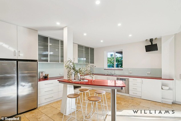 The sleek modern kitchen features stainless steel accents and dramatic red surfaces