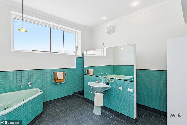 The striking modern bathroom with aquamarine tiles and deep spa bath has a modern, art-deco charm